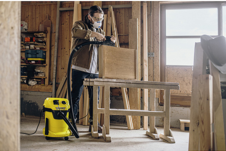 Osoba použva na čistenie dielne viacčelov vysvač KRCHER.