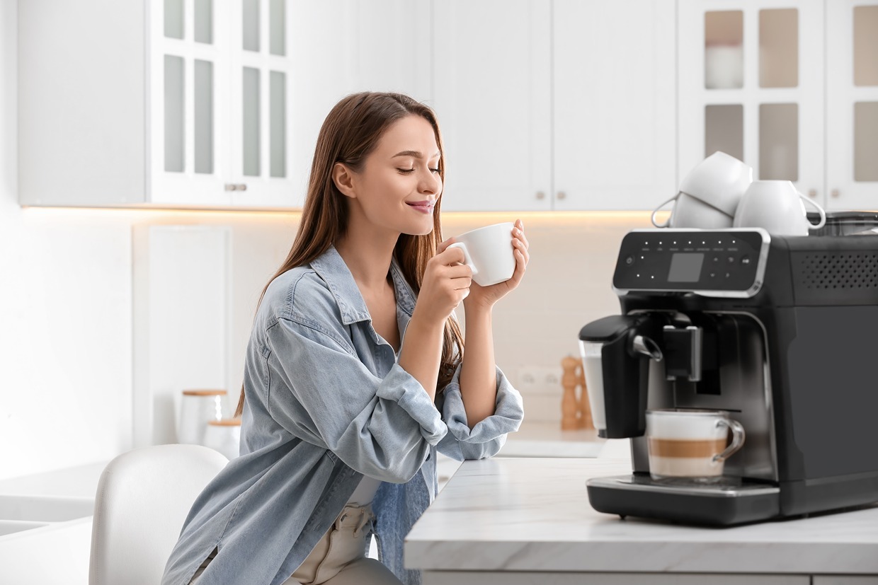 Osoba si vychutnáva kávu, ktorú pripravil automatický kávovar.