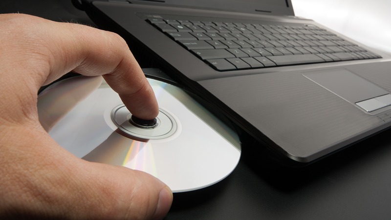 Muž vklad disk do PC, ktor je potrebn pre napaľovac software