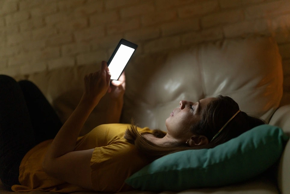 Čítanie podsvietenej elektronickej čítačky kníh v tme.