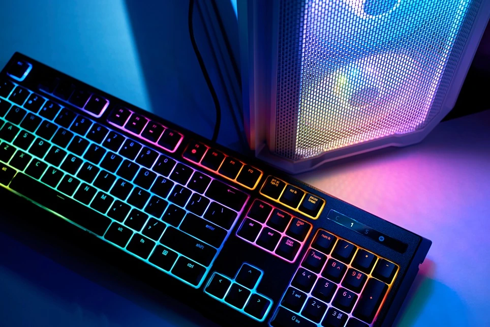 Herná klávesnica s RGB podsvietením vedľa počítača.